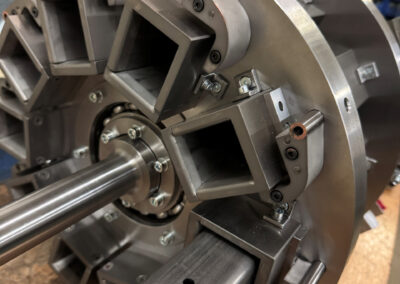 Nahaufnahme einer massiven, präzise gefertigten Drehvorrichtung (Rundtaktvorrichtung) aus Metall, die auf einer hölzernen Werkbank steht.